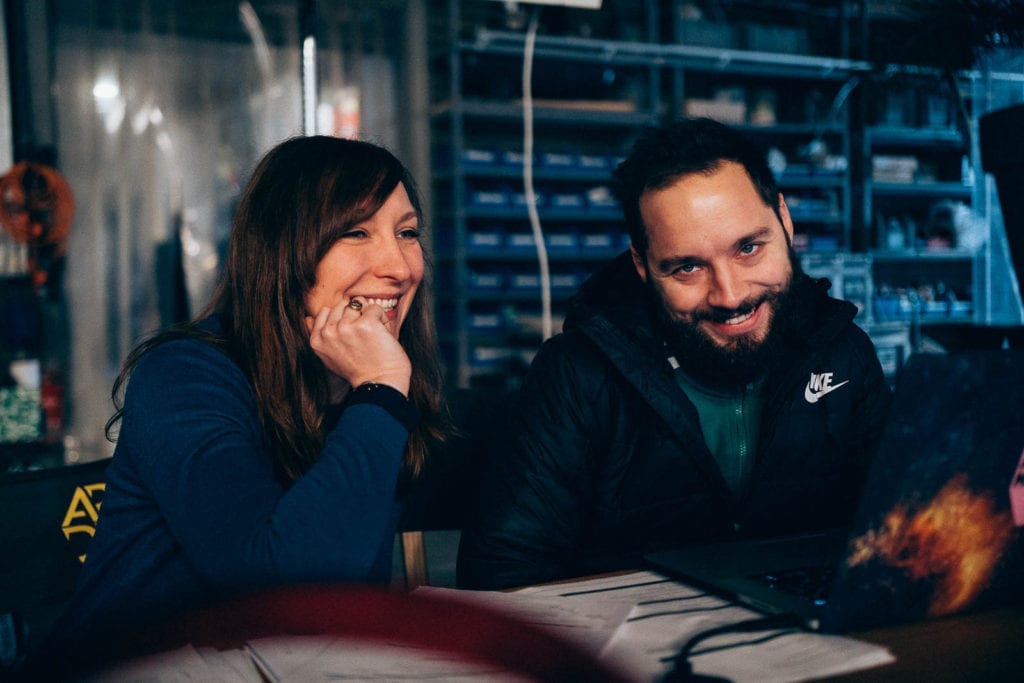 Squareme Mesi medical devices video - director Luka Štigl and production coordinator Tjaša Kocjan sitting behind a desk on set in a studio with equipment in the background